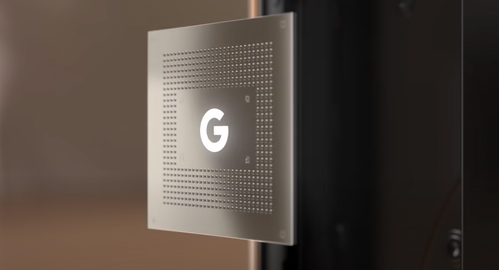 A rendering of the Google Tensor chip with a G logo on it, floating in front of a blurred background